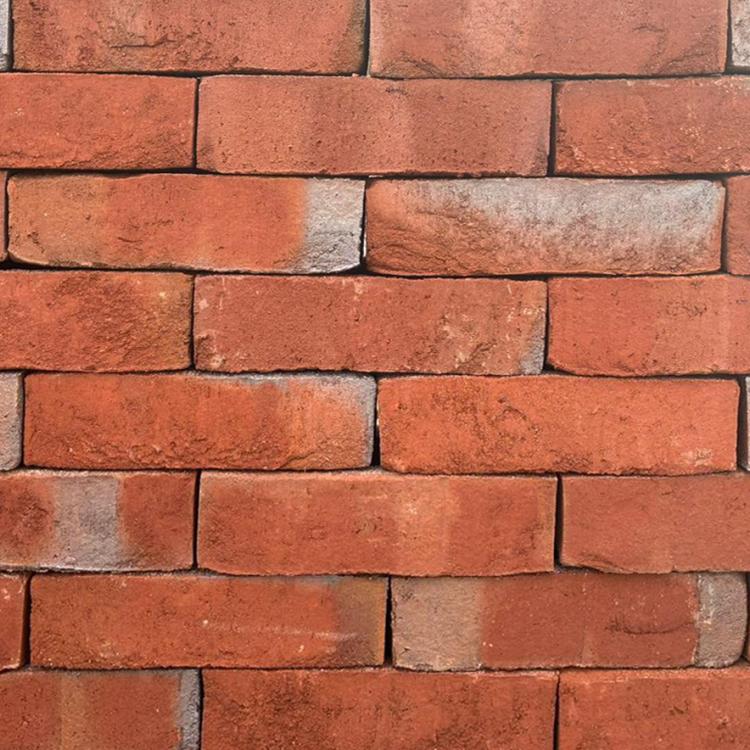 Rote Ziegelsteinmauer mit leichten Verfärbungen.