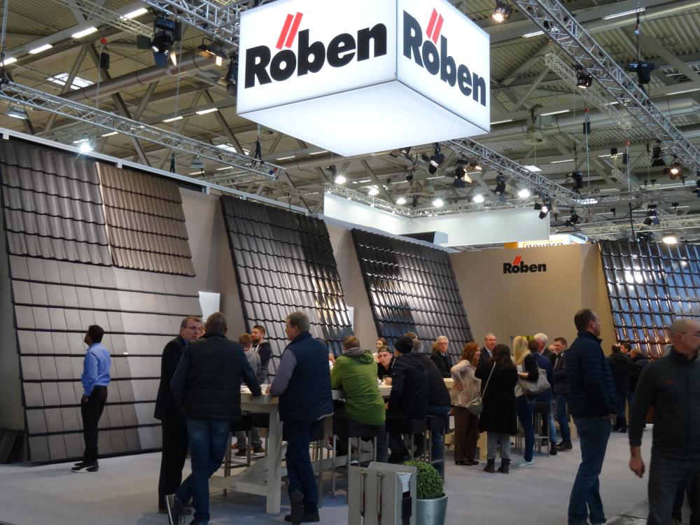 Menschen bei einer Messe an einem Stand mit Dachziegeln und dem Logo "Röben".