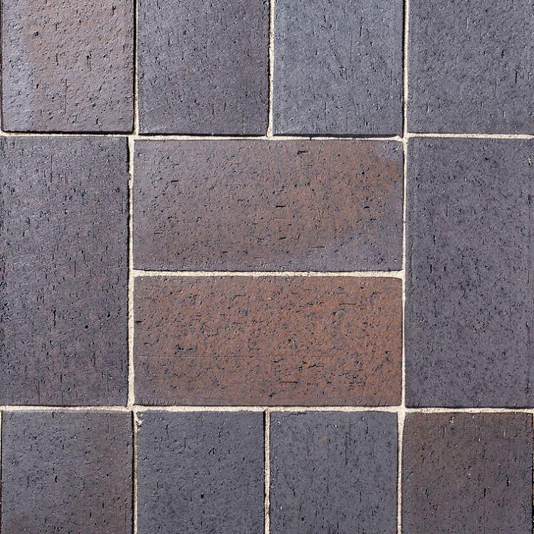 Ziegelmauer mit dunkelgrauen und graubraunen Steinen.