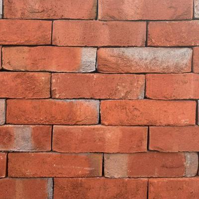 Rote Ziegelsteinmauer mit leichten Verfärbungen.