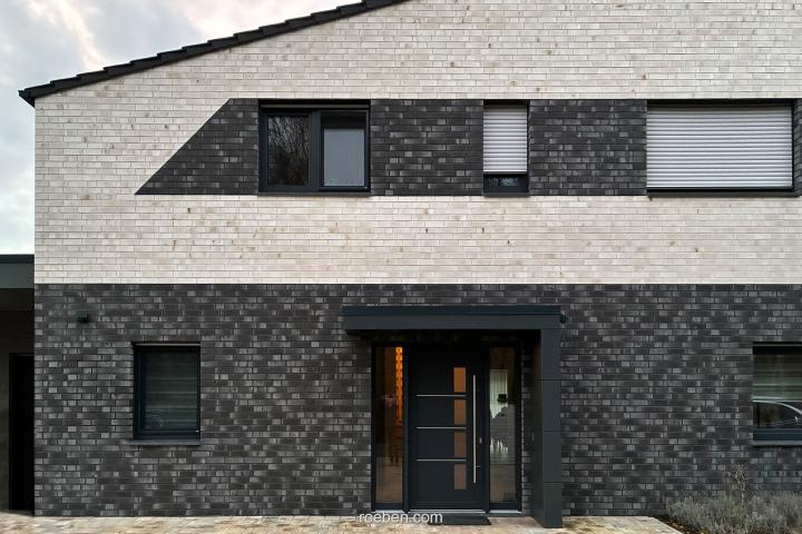 Zweistöckiges Haus mit schwarzer und weißer Ziegelfassade.
