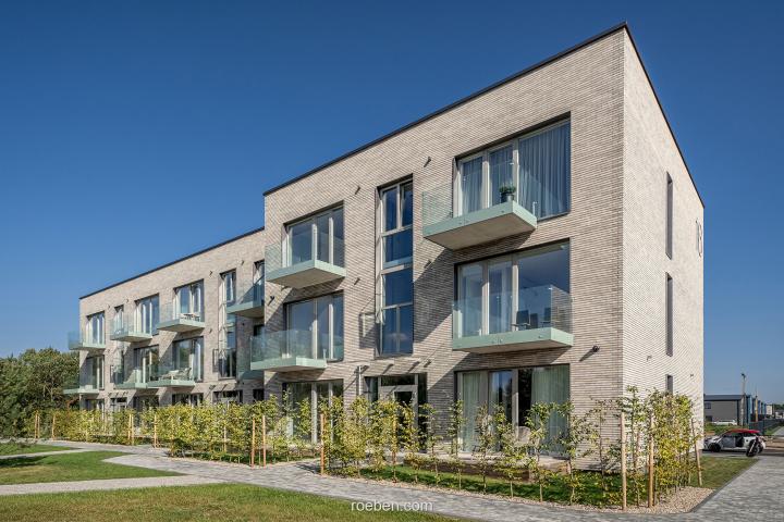 Moderne Wohnanlage mit Balkonen, blauer Himmel im Hintergrund.
