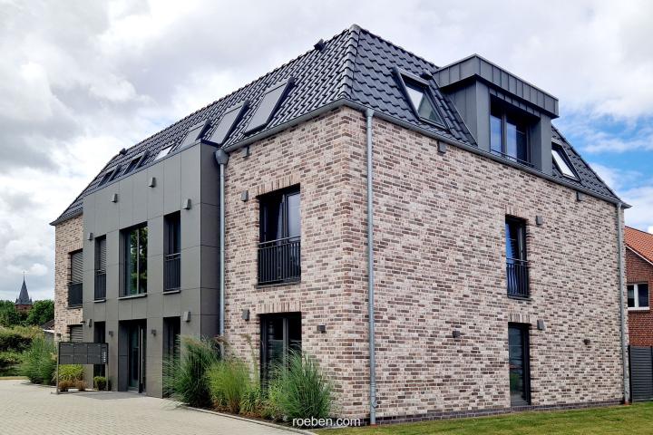 Modernes zweistöckiges Haus mit Ziegelfassade und Schrägdach unter bewölktem Himmel.