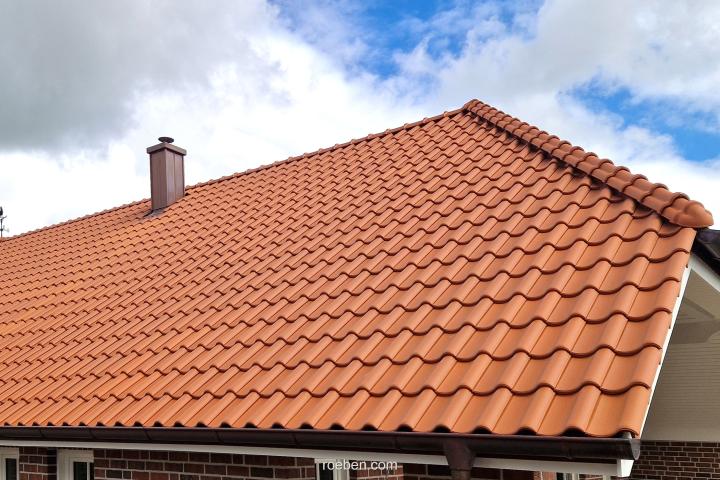Rotes Ziegeldach unter blauem Himmel mit Wolken.