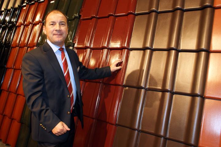 Mann im Anzug vor bunter Fliesenwand aus Metall.