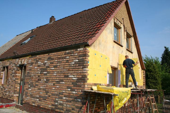 Dämmung und eine neue Fassade (Handformverblender MOORBRAND torf-bunt) werden vor die alte Putzfassade gesetzt. Oben im Giebel noch das alte Klinker-Imitat.