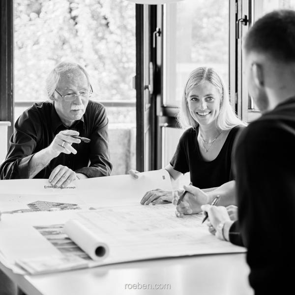 Architekten Hilmes-Lamprecht in einem Meeting um einen Tisch.