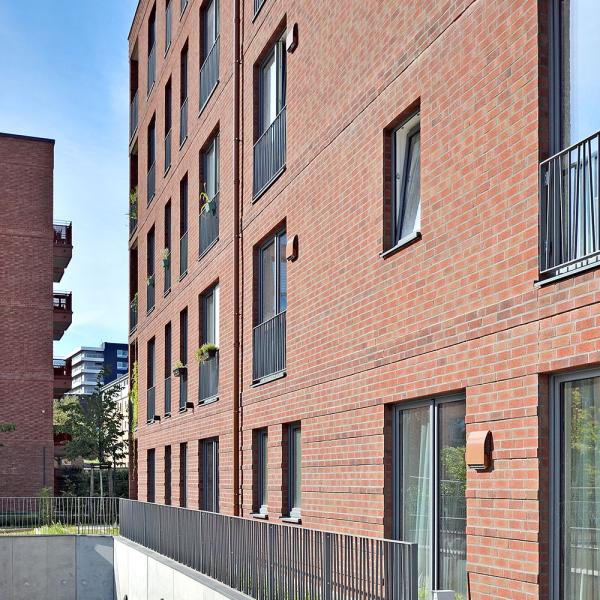 Moderne Backstein-Gebäudefassade bei sonnigem Wetter.