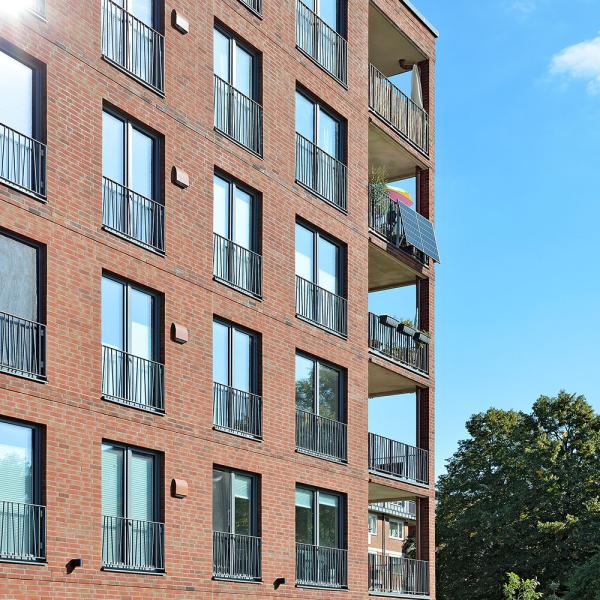 Fünfstöckiges Backsteingebäude mit Balkonen, sonniger Tag.