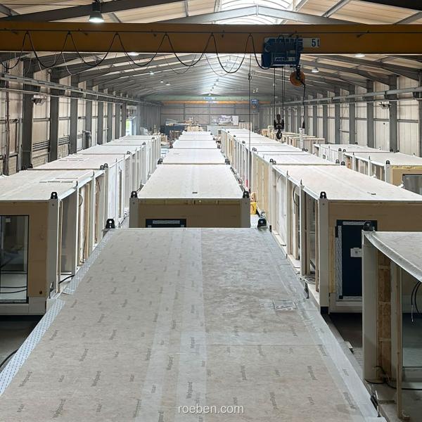 Fabrikhalle mit modularen Häusern in Reihen.